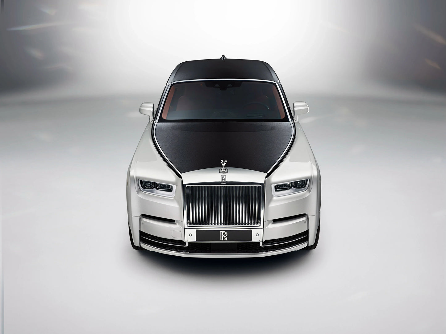Front view of 2017 Rolls-Royce Phantom luxury car with black hood and silver body on gray background