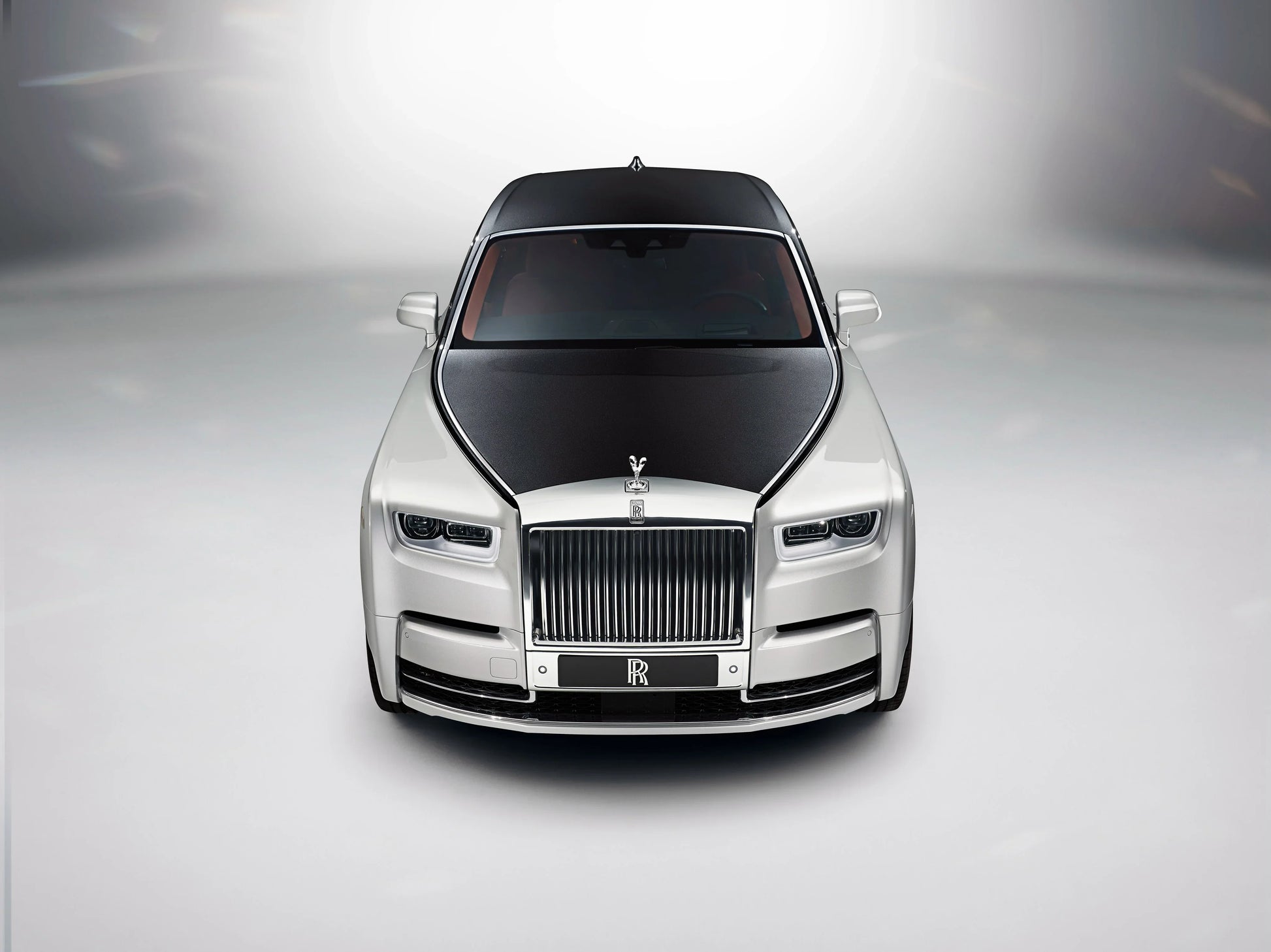 Front view of 2017 Rolls-Royce Phantom luxury car with black hood and silver body on gray background