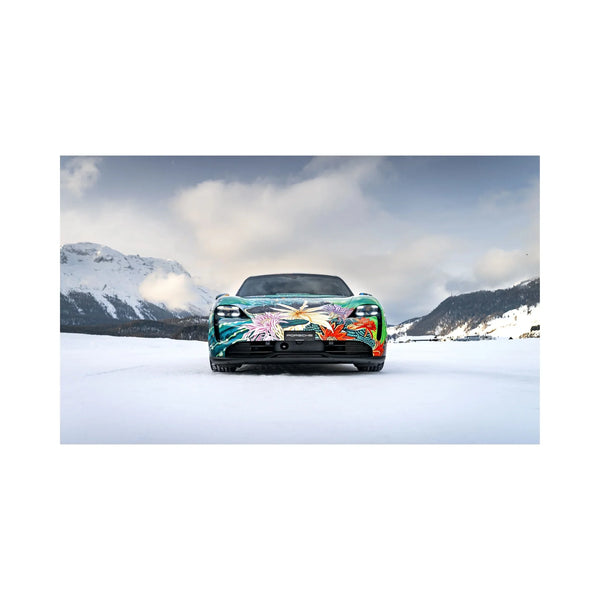 Front view of a Porsche sports car with colorful floral art wrap on snowy mountain landscape