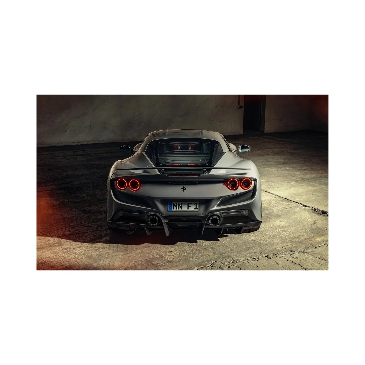 Rear view of silver Ferrari F8 Tributo sports car with quad circular taillights in dim garage