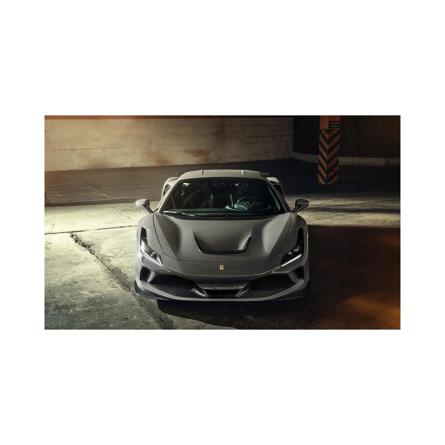 Gray Ferrari sports car parked inside industrial garage with textured concrete floor