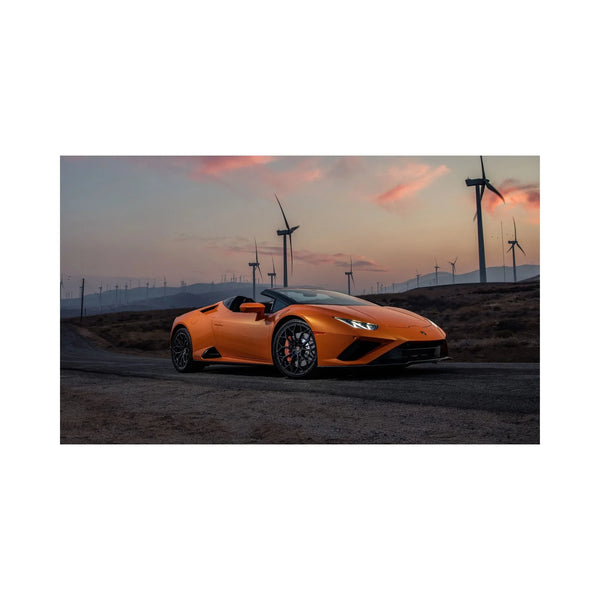 Orange Lamborghini Huracan Spyder on rural road at sunset with wind turbines in the background
