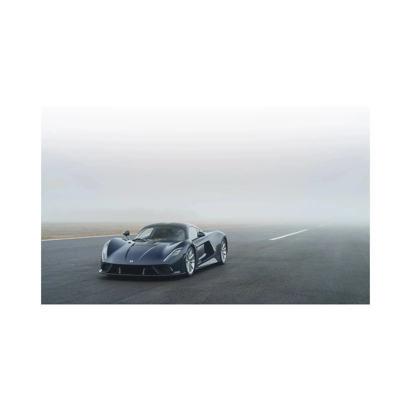 Black sports car parked on foggy tarmac road with overcast sky in background
