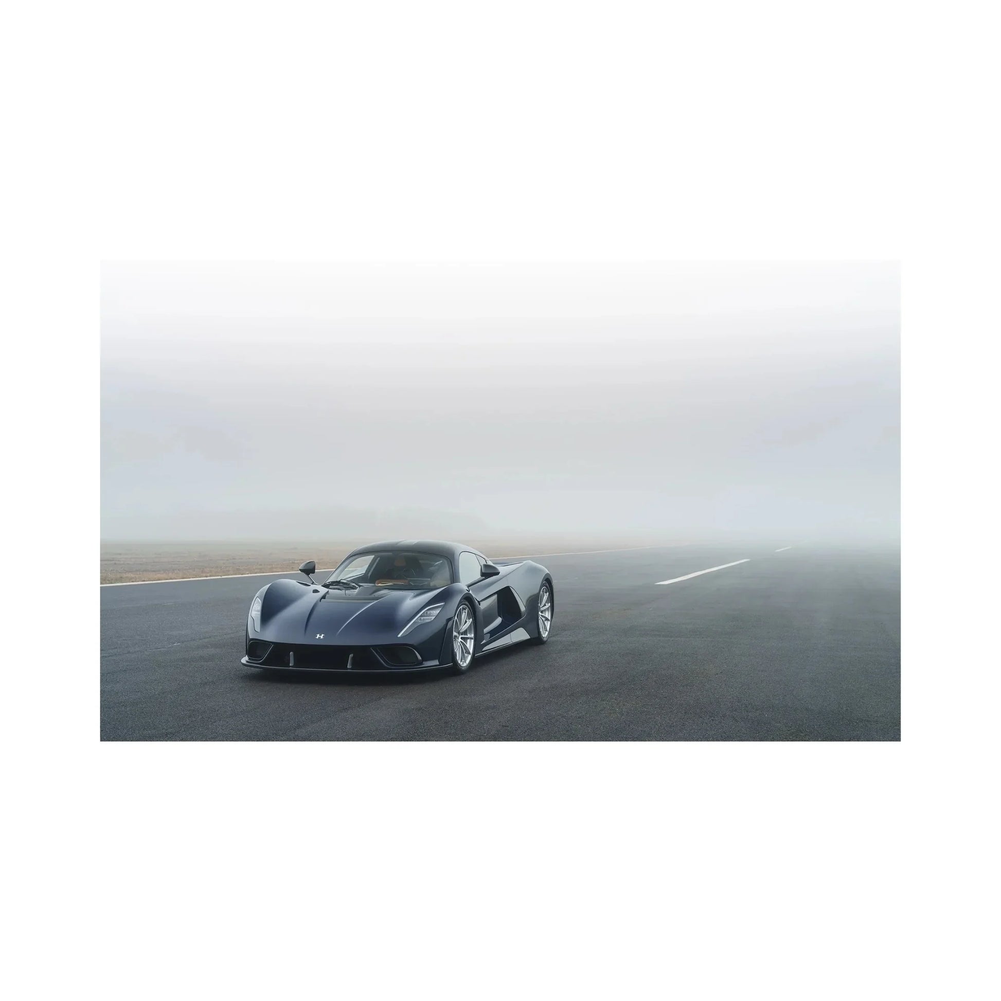 Black sports car parked on foggy tarmac road with overcast sky in background
