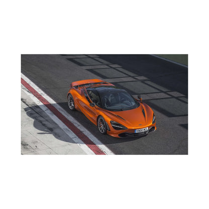 Orange McLaren sports car parked on race track next to red and white curb